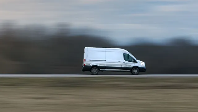 Hvit varebil i høy fart på motorvei, med uskarp bakgrunn som viser bevegelse.